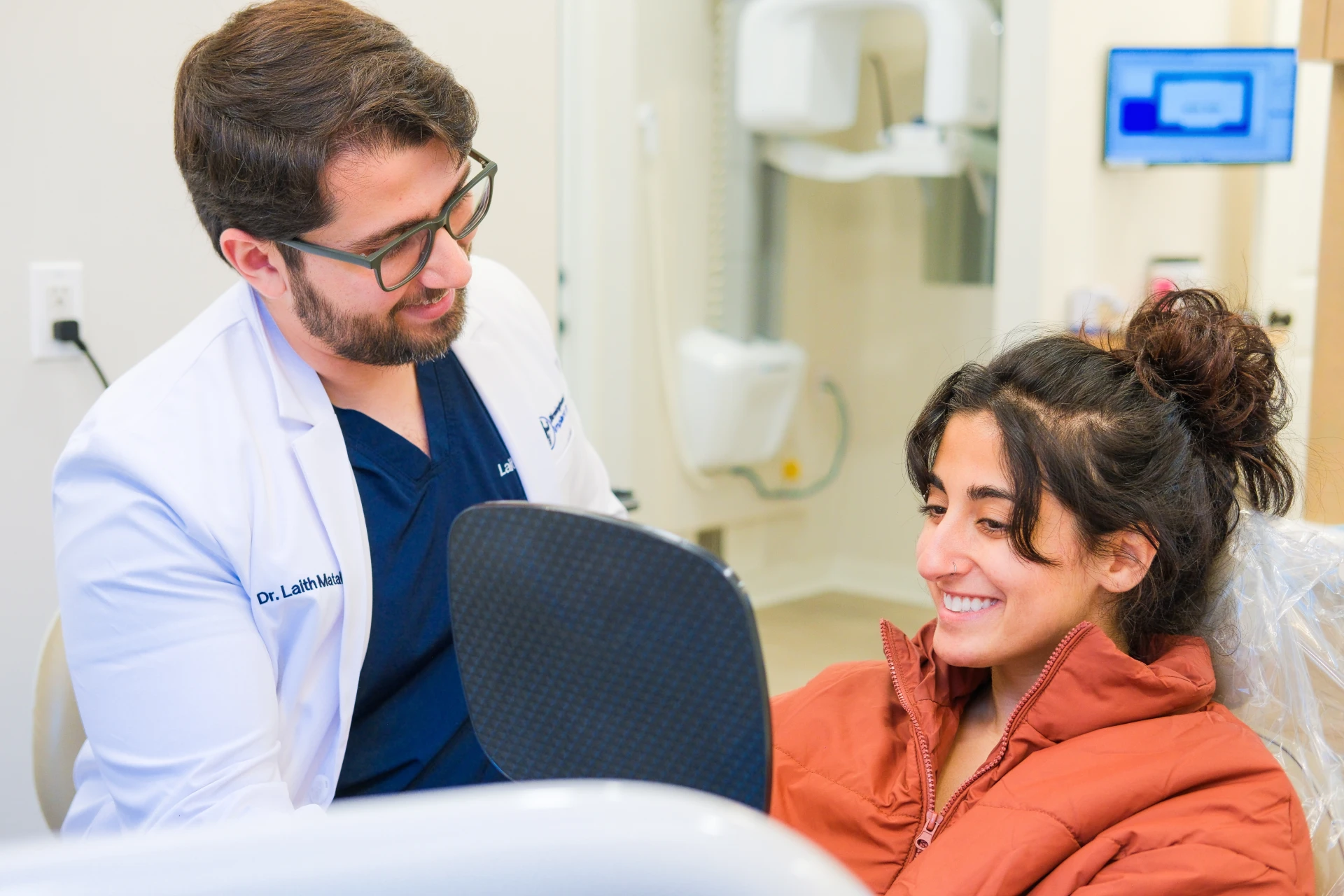 Patient smiling in mirror seeing new smile after dental implant treatment in Birmingham, Alabama